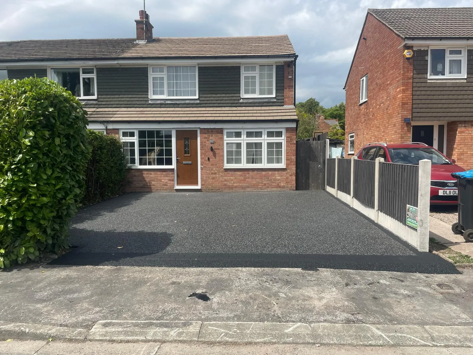 Black resin bound driveway at grey semi-detached home