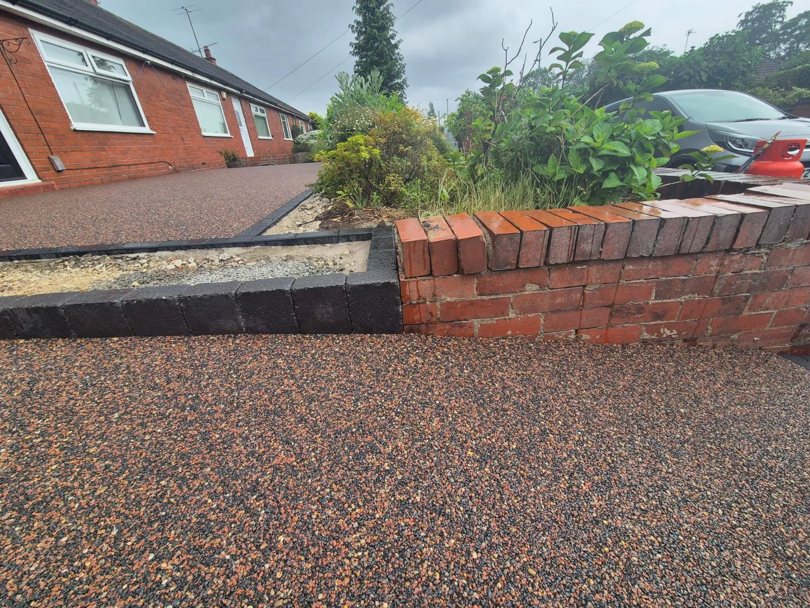 Bronze resin drive with red brick wall border