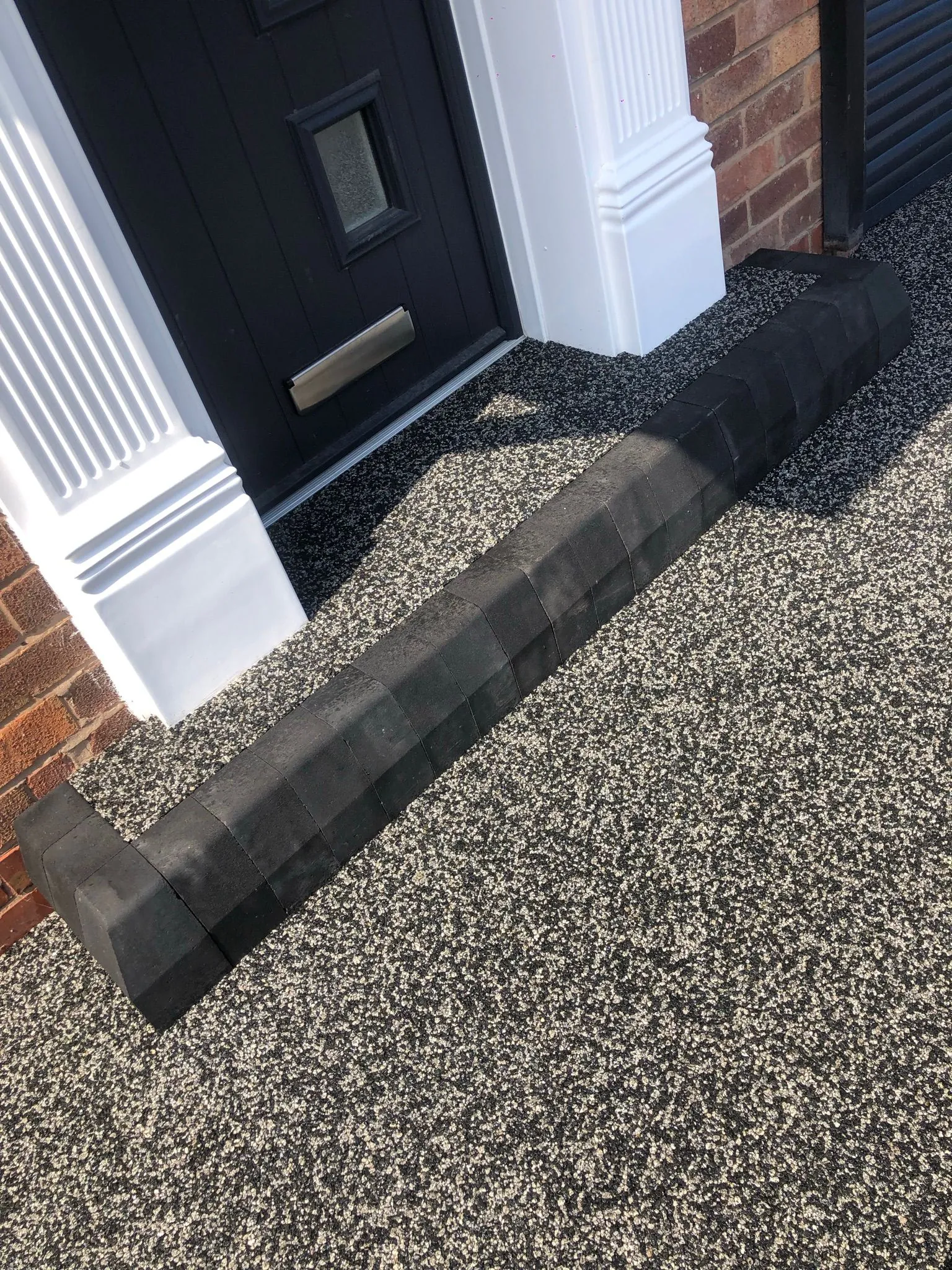 Charcoal resin drive at black door with kerb detail
