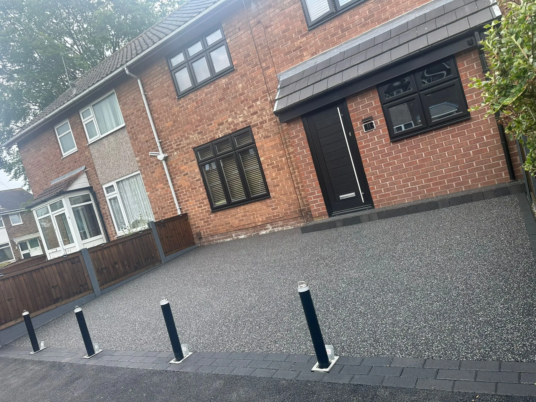 Charcoal resin drive with bollards at red brick home