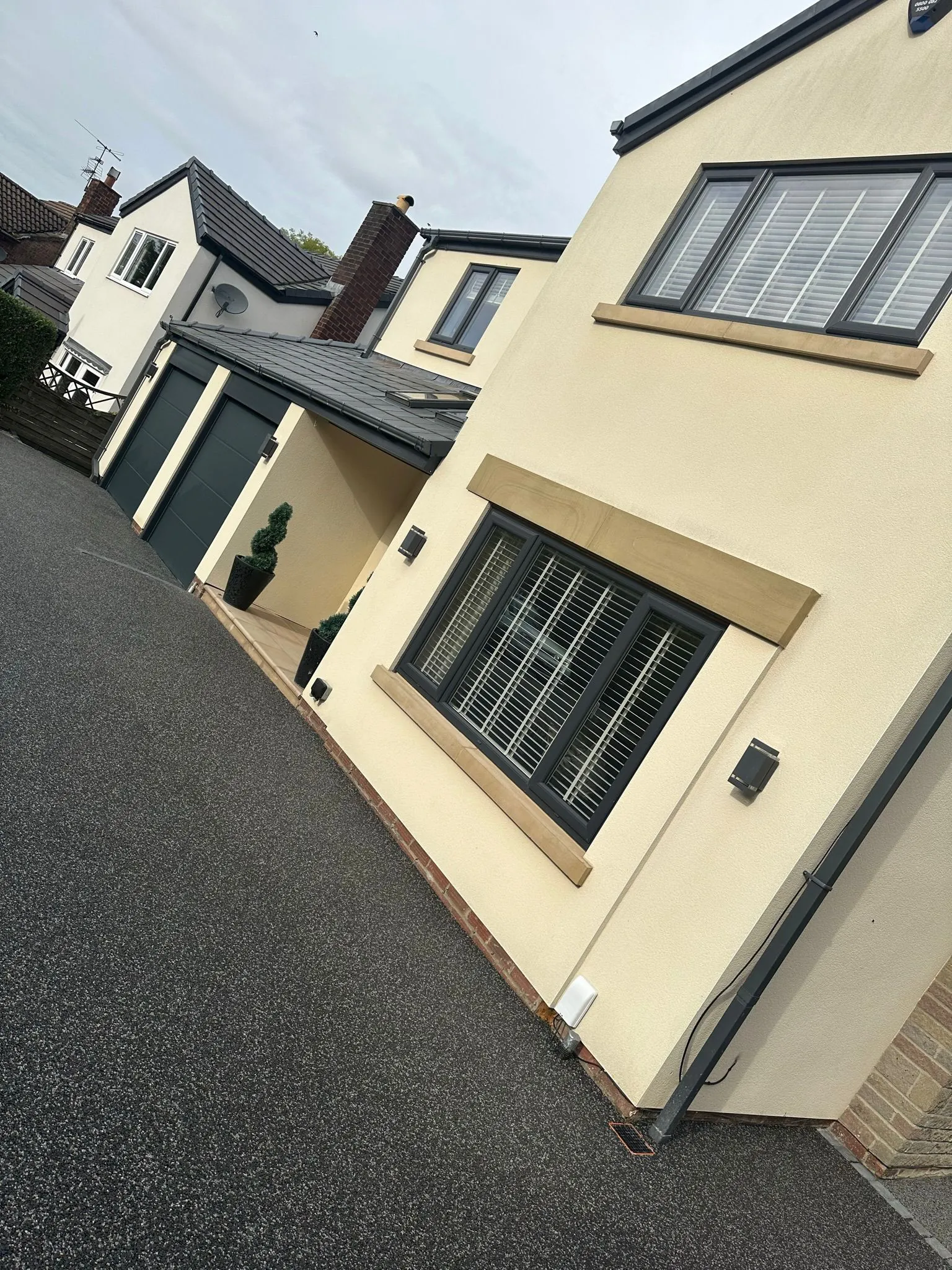 Charcoal resin drive at cream rendered home, Manchester