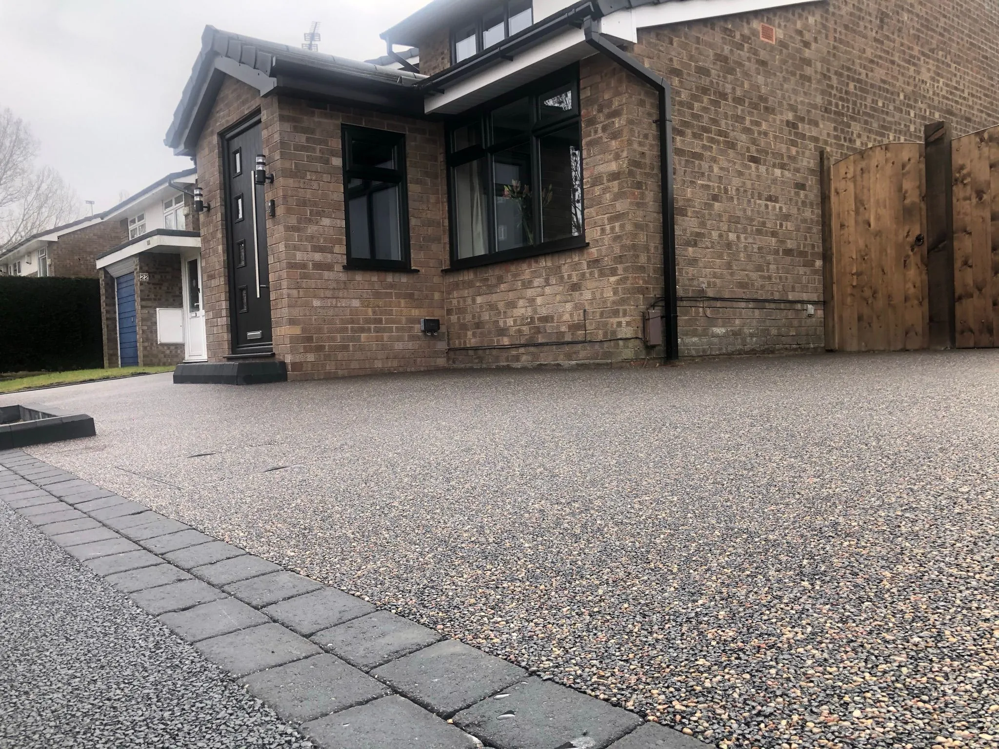 Charcoal resin drive at new build with brick garden wall