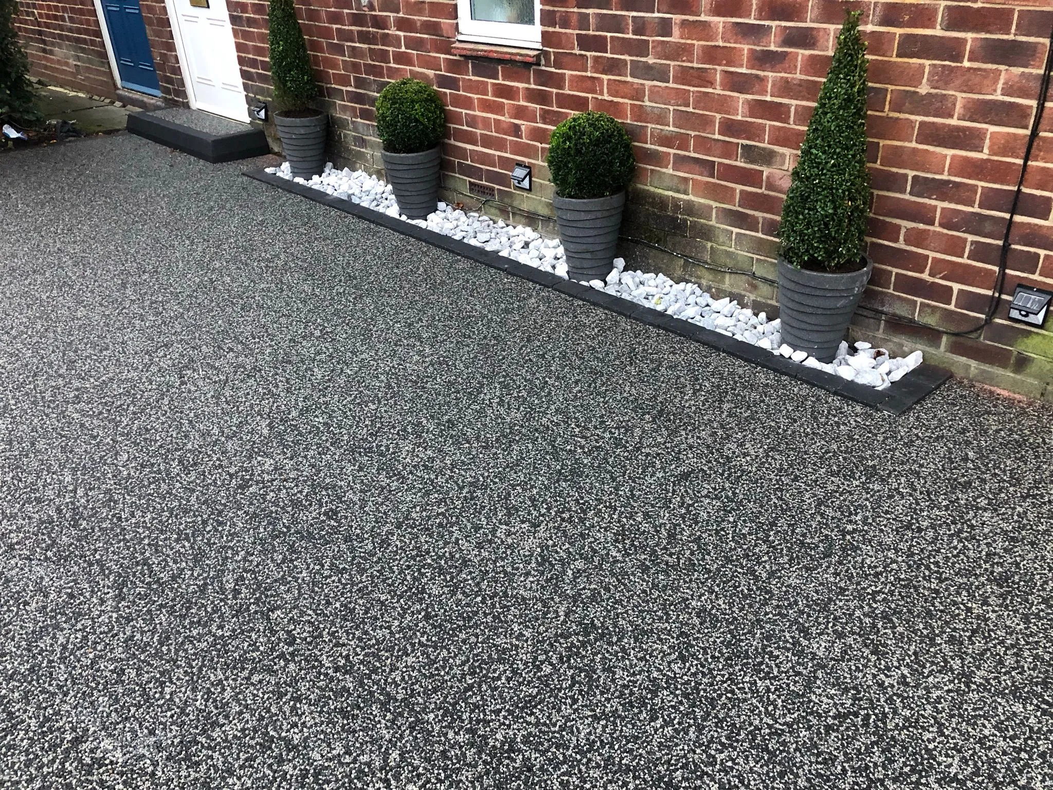 Charcoal resin drive with topiary and white pebble border