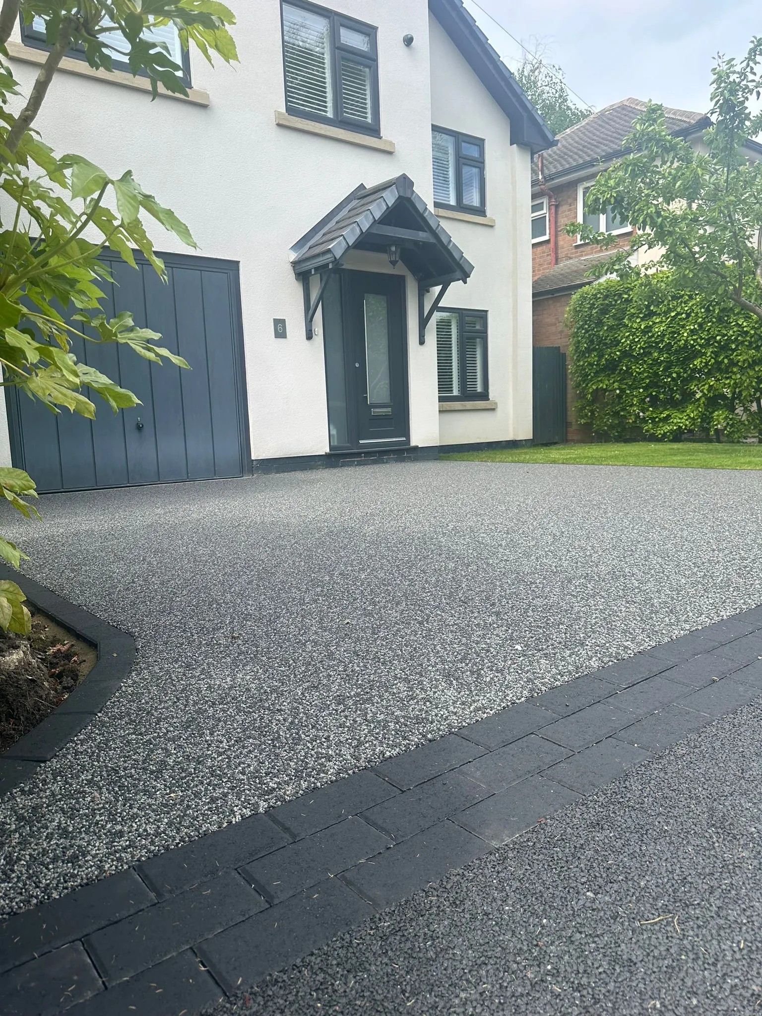 Charcoal resin drive at white rendered home, front view