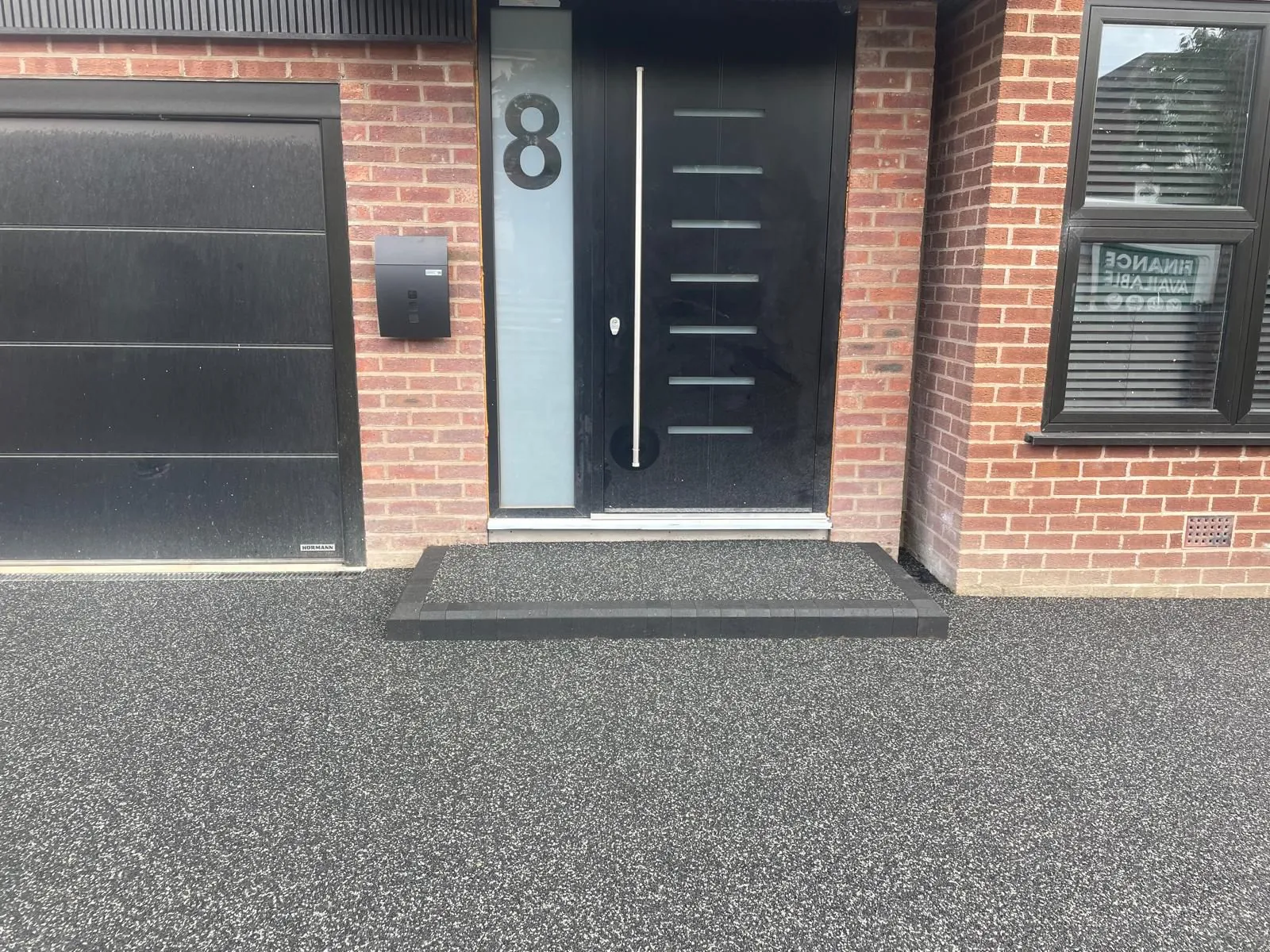Charcoal resin driveway with modern black door entrance