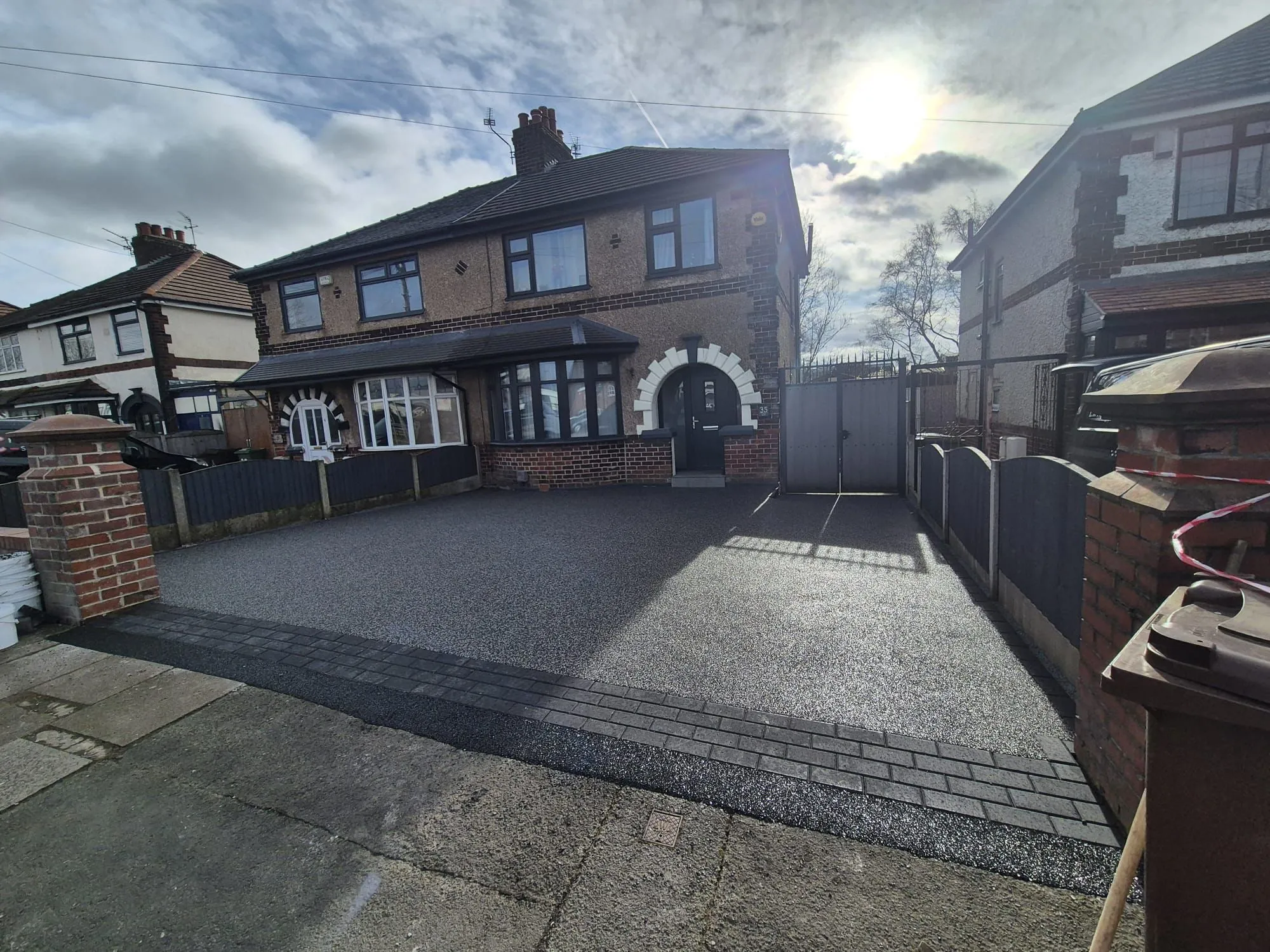 Dark grey resin bound driveway with brick pier entrance