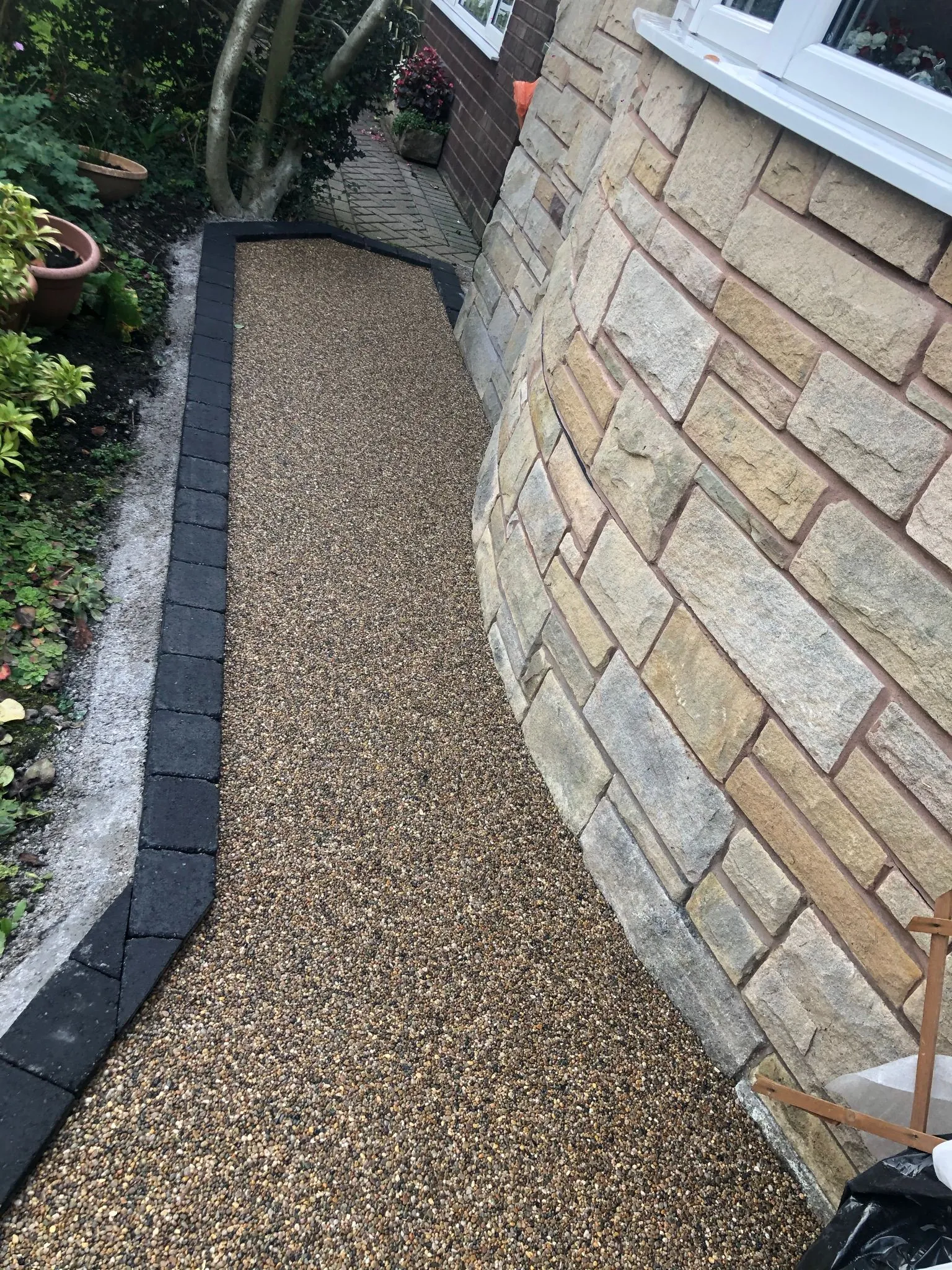 Gold resin garden path alongside stone wall, Manchester