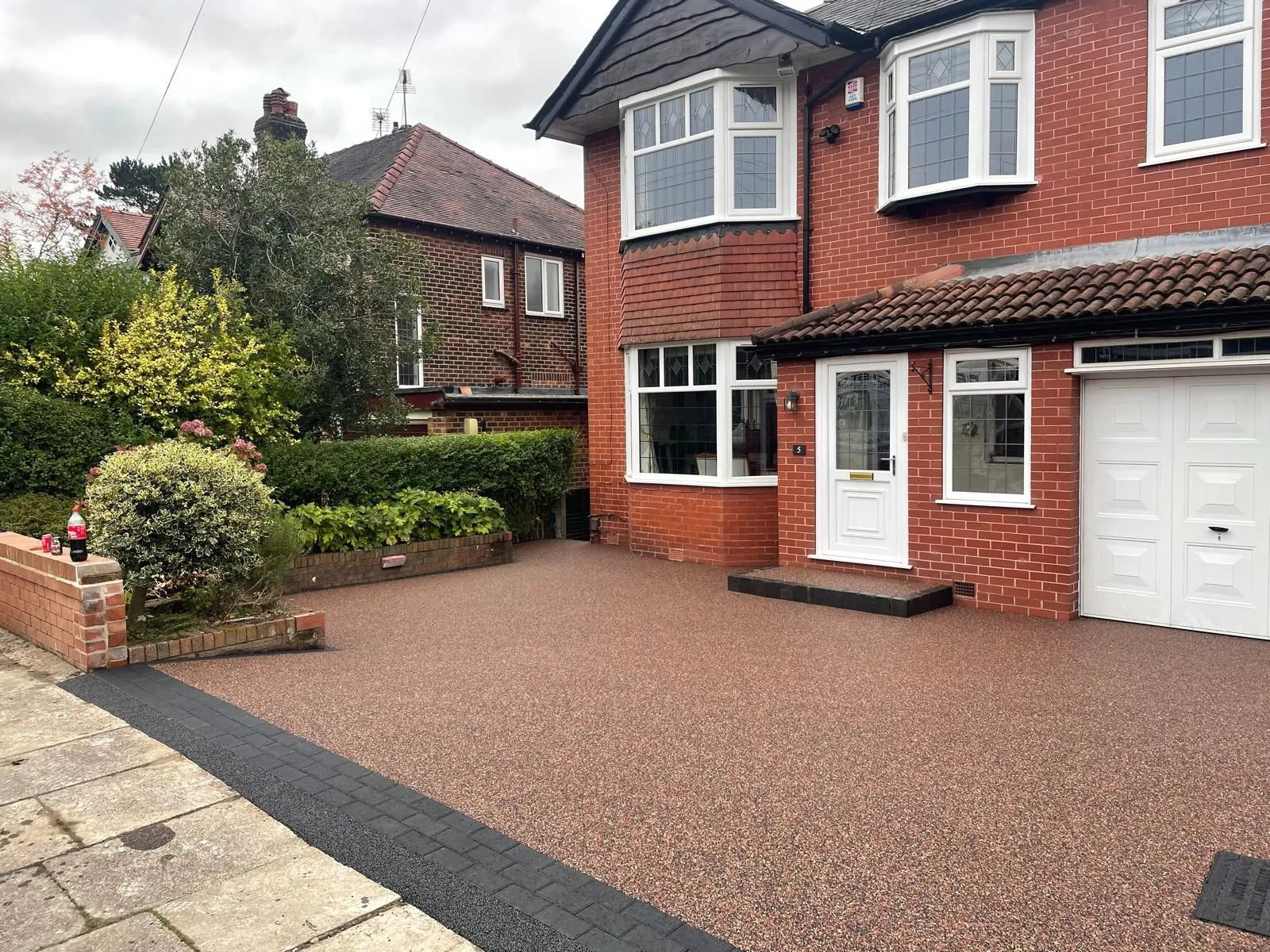 Russet resin bound driveway at red brick bay-fronted home
