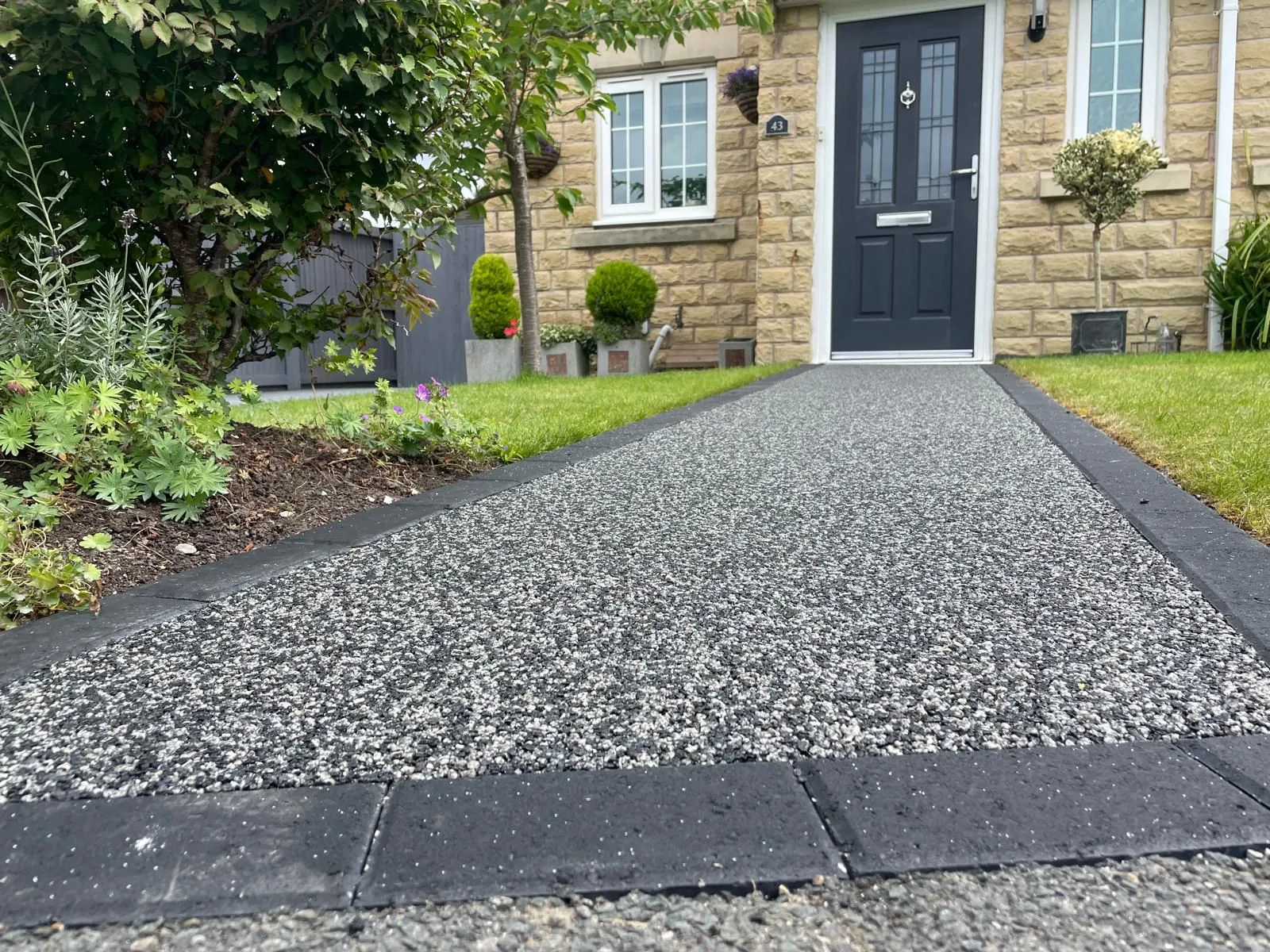 Silver resin drive at stone cottage with block paved border
