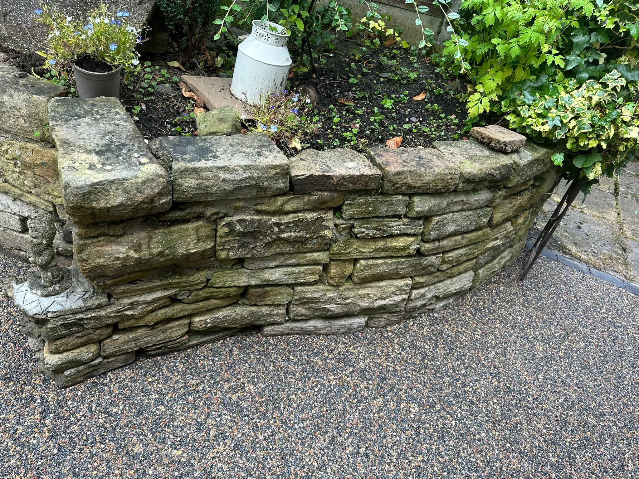 Stone wall feature alongside resin drive and garden