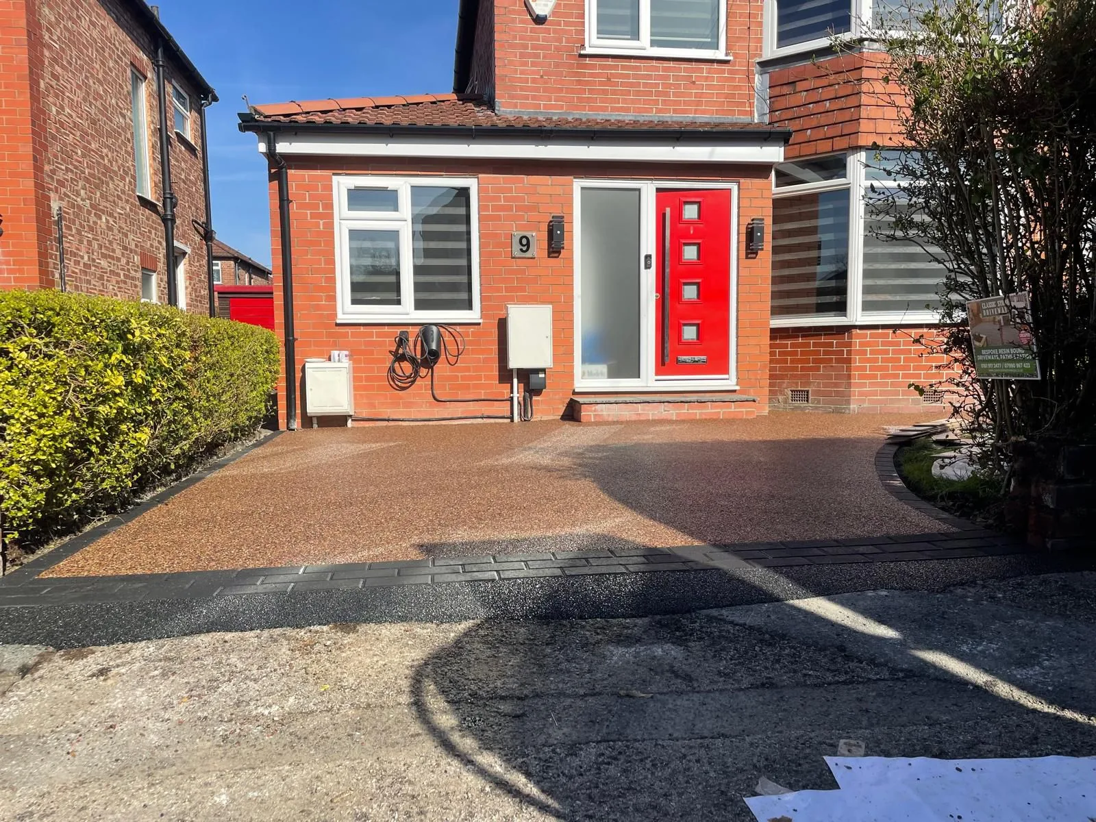 Brown resin driveway at a red-door semi-detached house, Manchester