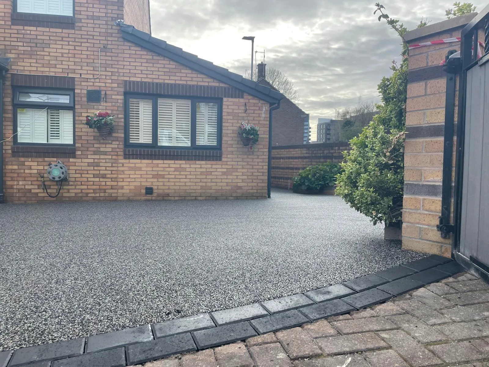Charcoal resin driveway with block-paved border at a bungalow, Manchester