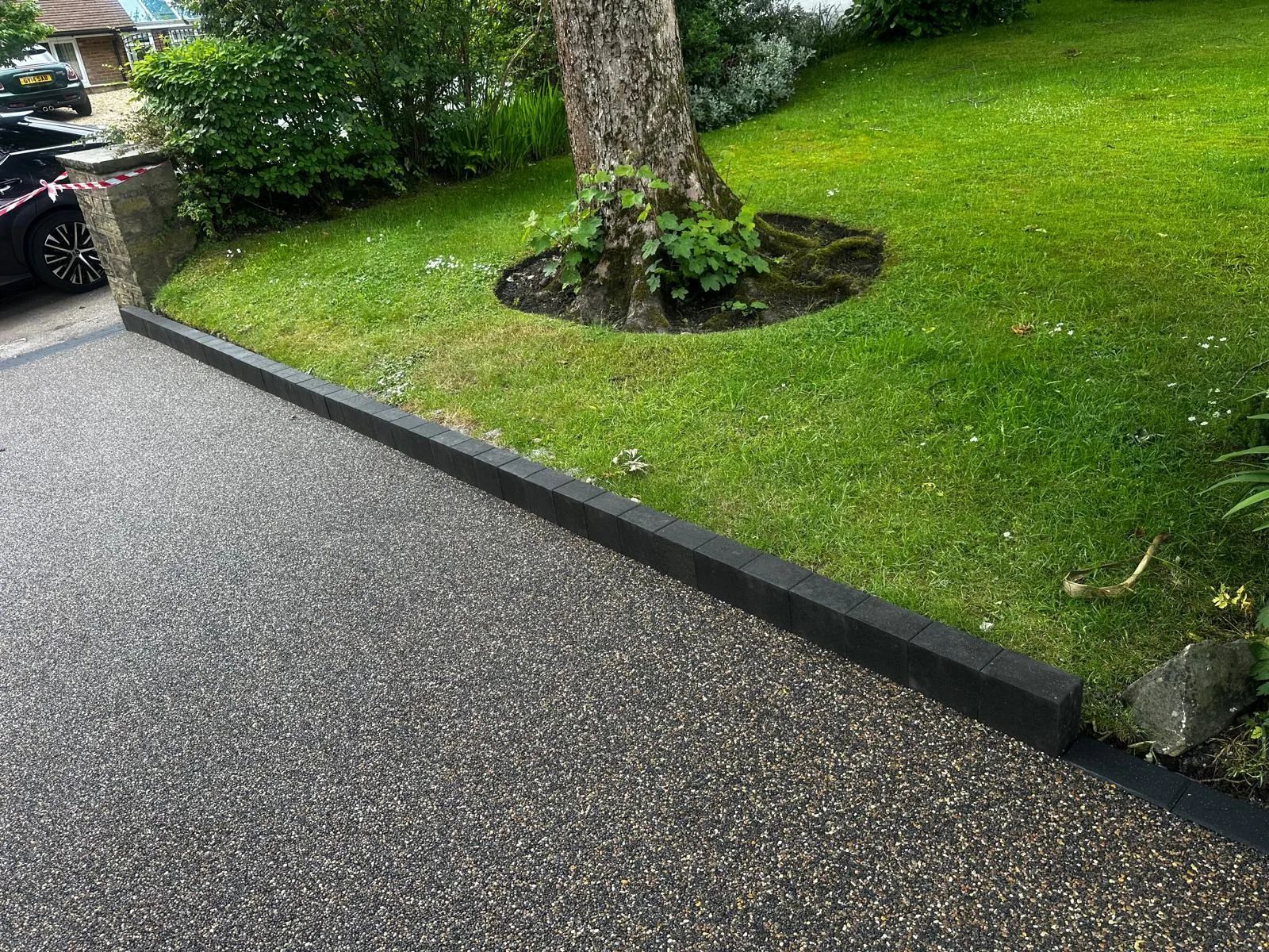 Charcoal resin driveway beside a mature garden lawn and tree, Manchester