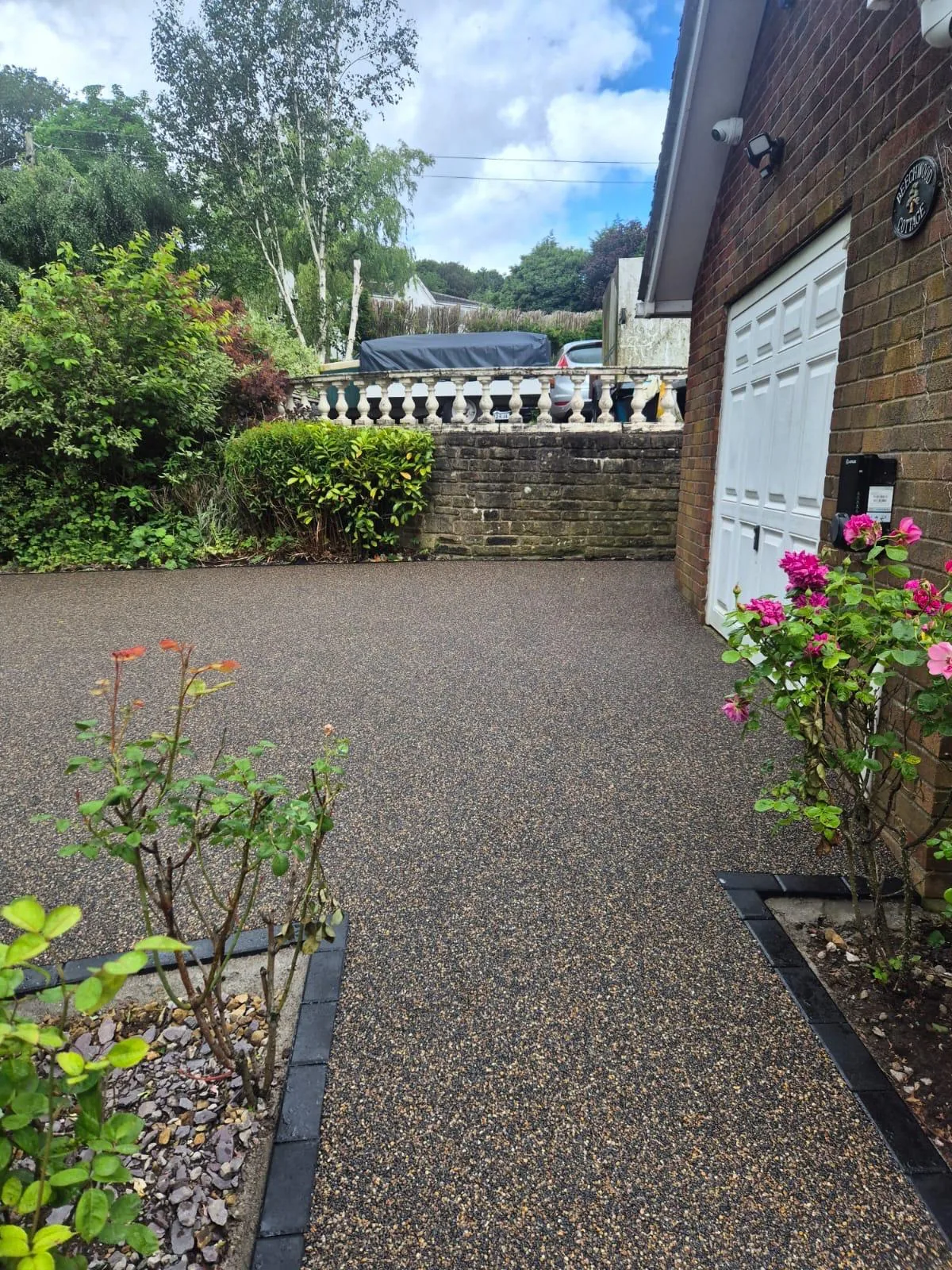 Copper resin driveway through a front garden with roses, Manchester