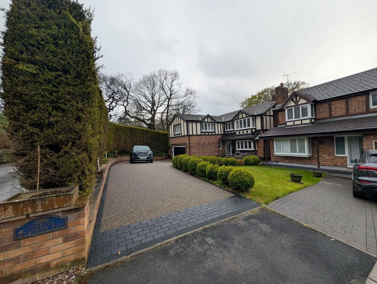 Golden resin driveway sweeping up to a detached mock-Tudor home in Glossop, with charcoal block apron at the road