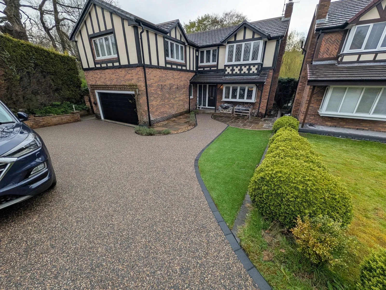 Golden resin bound driveway with charcoal block border at a detached mock-Tudor home in Glossop