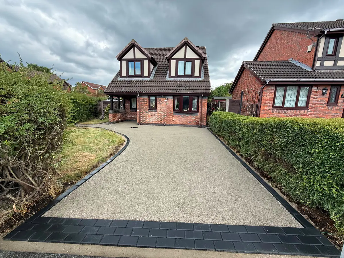 Black and silver resin bound driveway sweeping up to a dormer home in Hyde